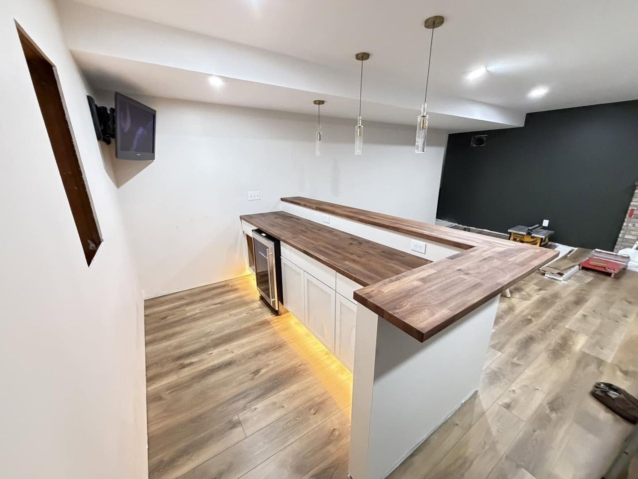 Basement bar with walnut butcher block counter and pendant lighting