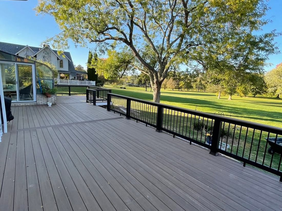 Finished main-floor composite deck with black aluminium railing beside the sunroom