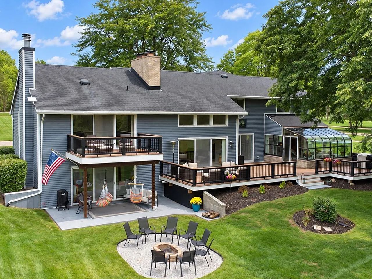 Raised view of the rear of the house showing the full deck, sunroom and yard
