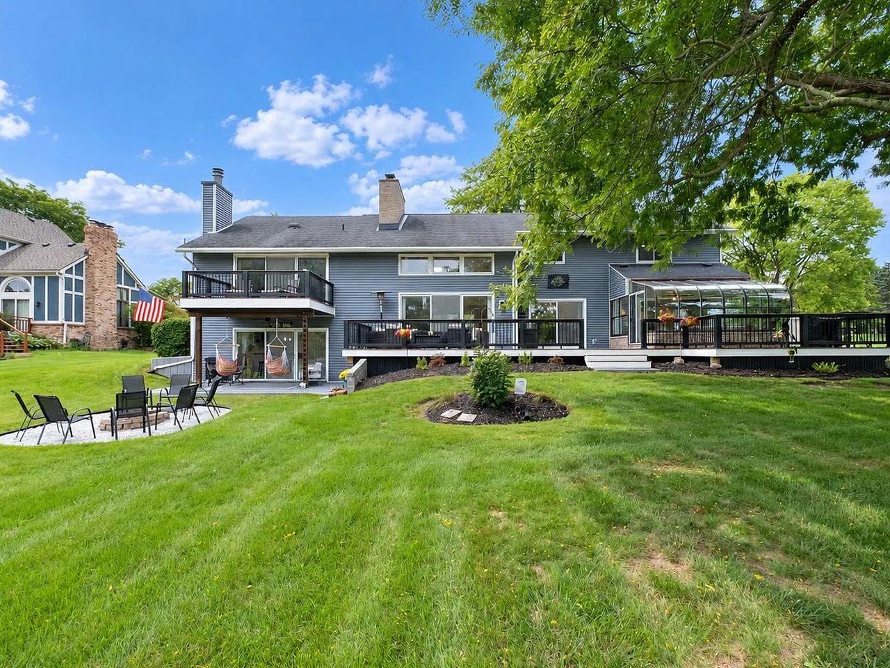 Rear of the house showing both deck levels, the sunroom and a fire pit on the lawn