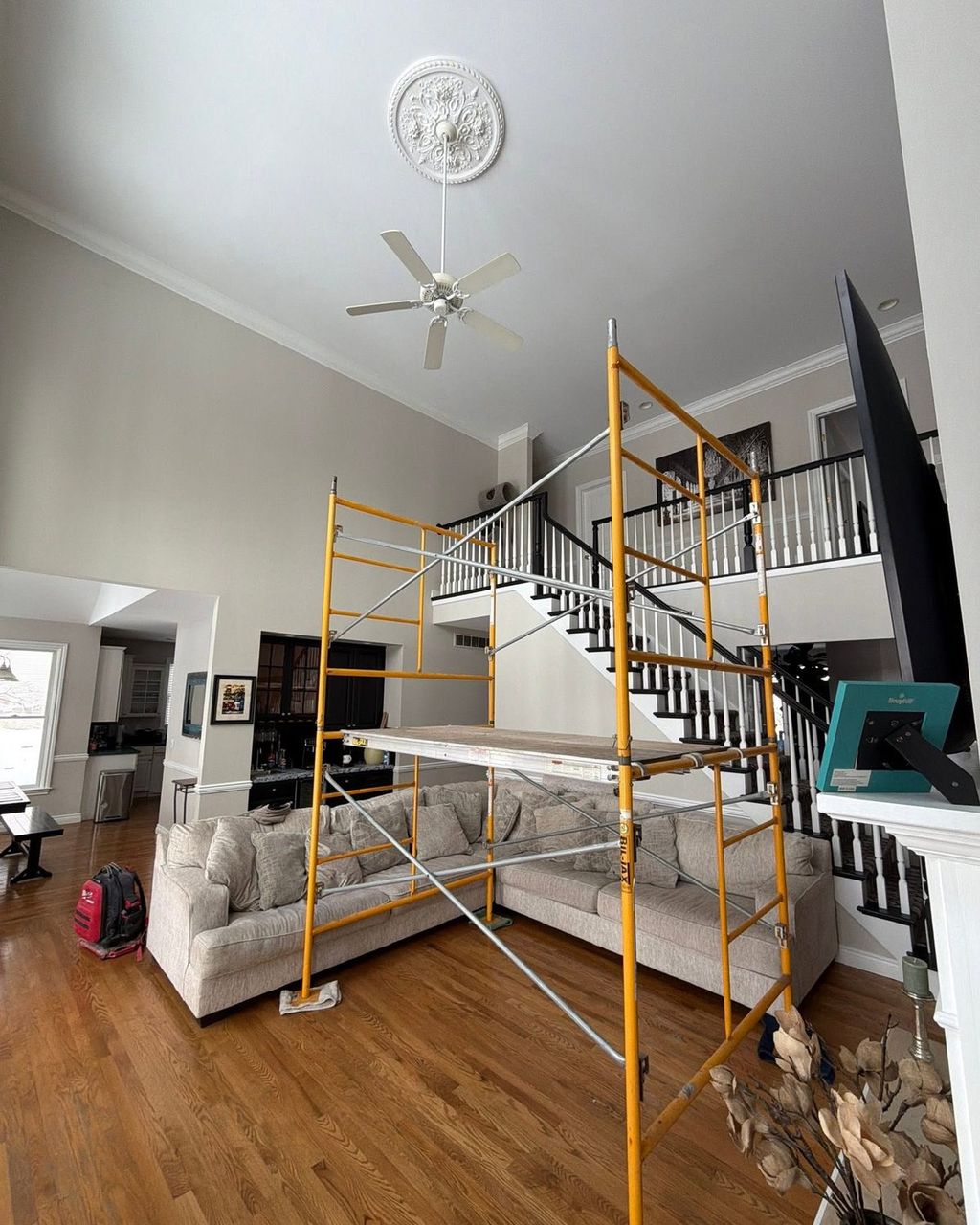Two-story great room with scaffolding set up and the original ceiling fan