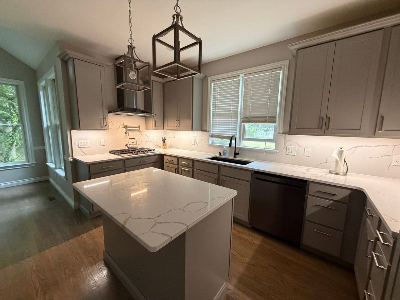 Kitchen range wall after remodeling, with vented hood, pot filler and quartz backsplash