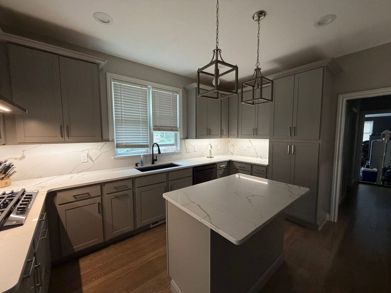 Kitchen after remodeling, grey shaker cabinets with white quartz countertops and full-height backsplash