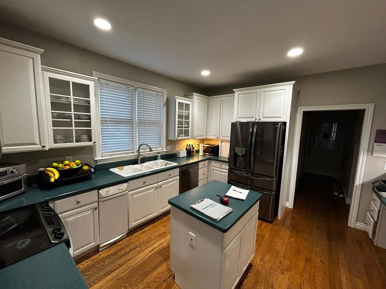 Kitchen before remodeling, white cabinets with dark green solid-surface countertops