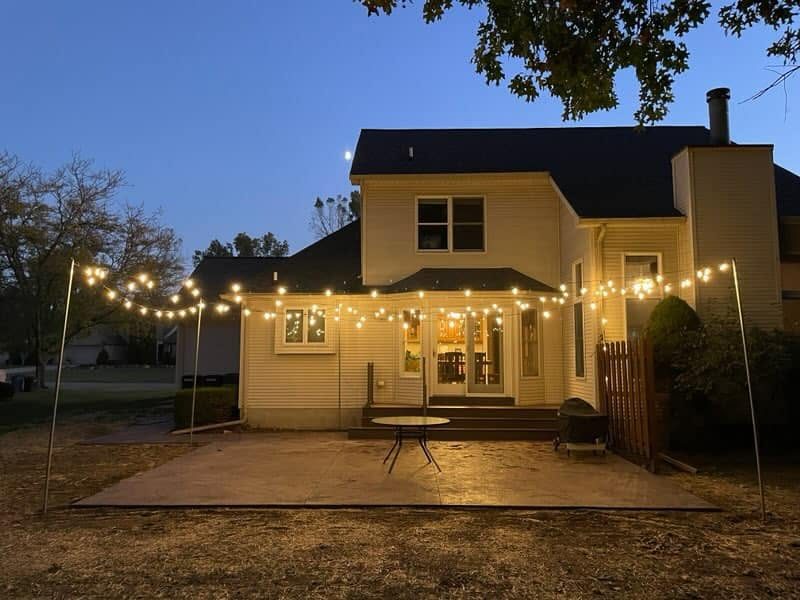 Concrete patio at dusk lit by overhead string lights