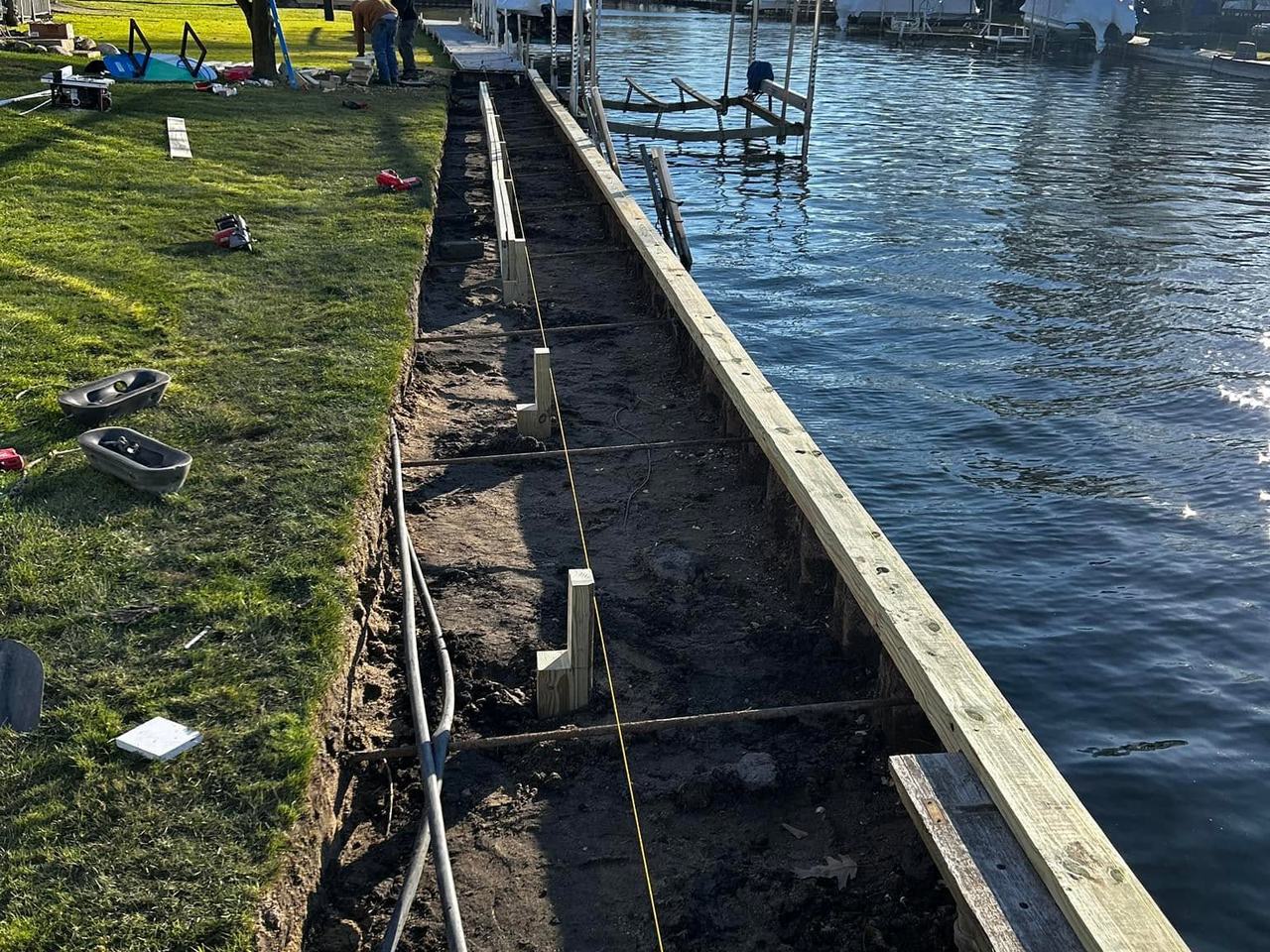 Shoreline excavated with a string line run and the first treated timber set along the water