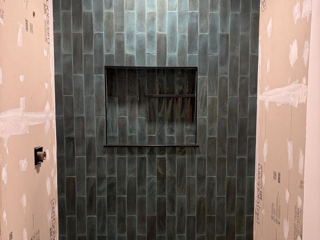 Shower walls tiled in vertical stacked tile with a recessed niche