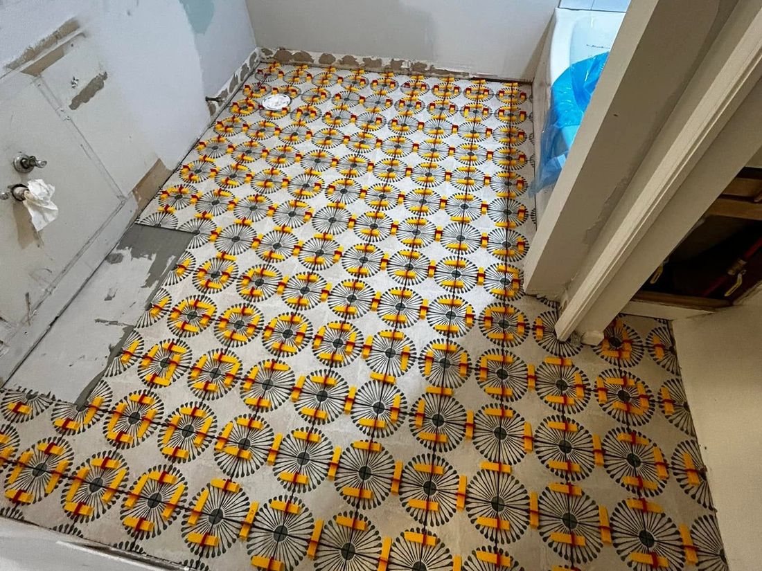 Patterned bathroom floor tile being set with levelling clips in place