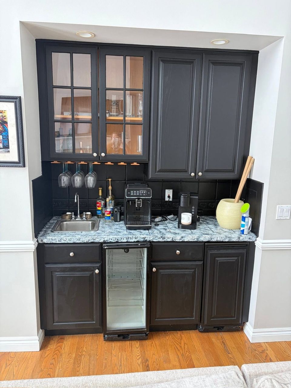 Wet bar before, with dark cabinets, granite top and tiled backsplash